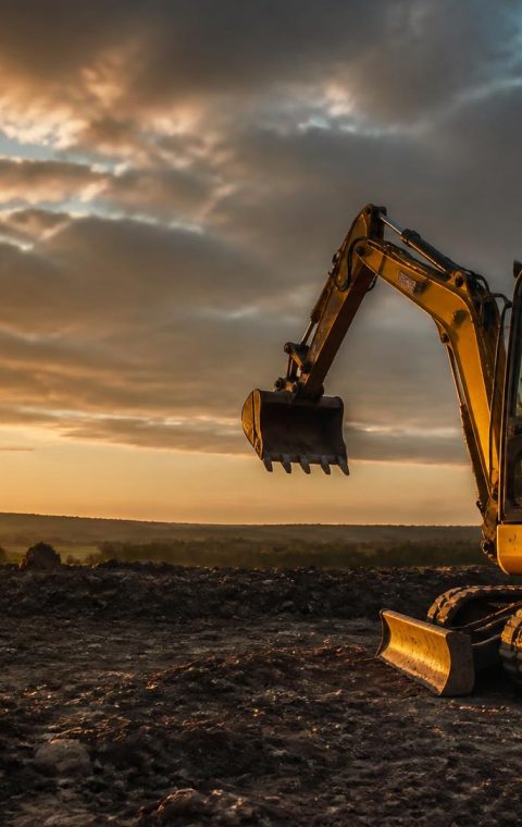 Tracked mini excavator standing on cleared ground at sunset on a North East England site
