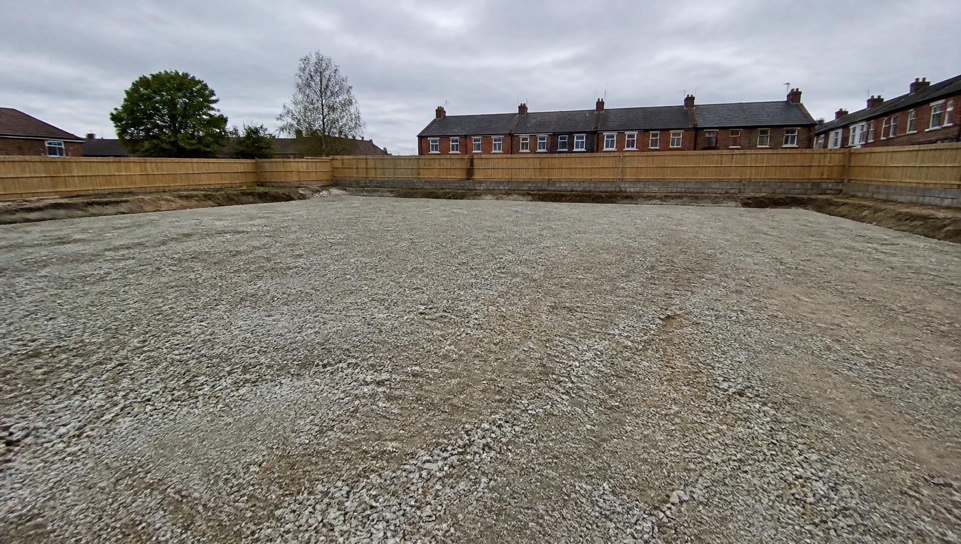 Broken-out hardstanding on a cleared plot, the kind of work the breaker attachment takes on